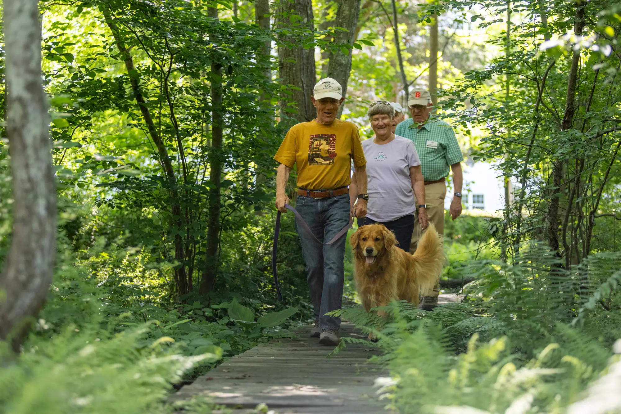 seniors walking through path outside while talking about what is a life plan community like StoneRidge, also a CCRC in Mystic, CT.