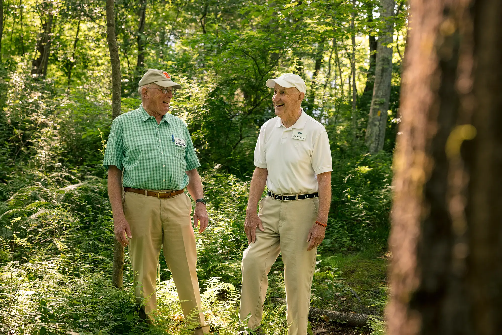 Two senior men standing in woods