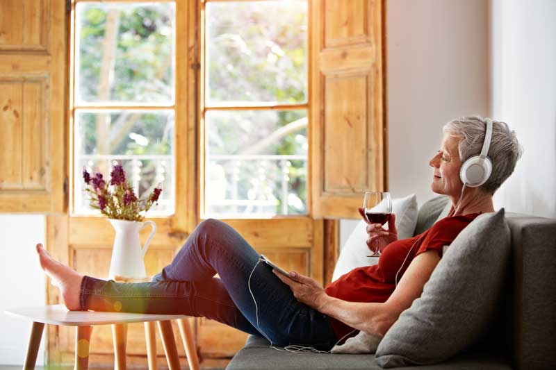 Senior woman listening to podcasts in her senior living apartment
