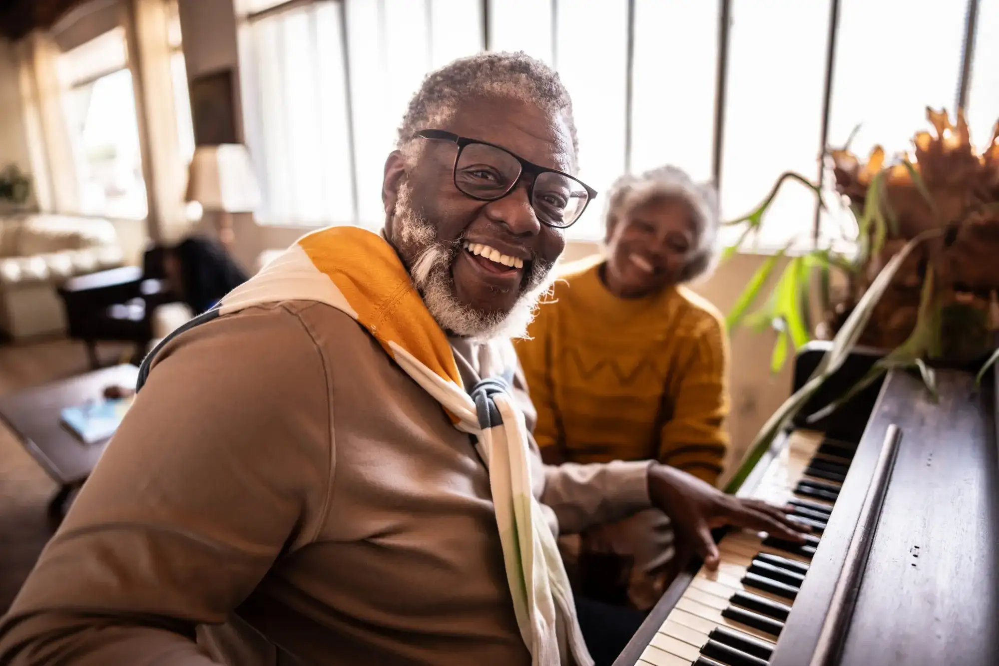 Senior man playing piano next to senior woman. The are exploring culturally curious events at StoneRidge.