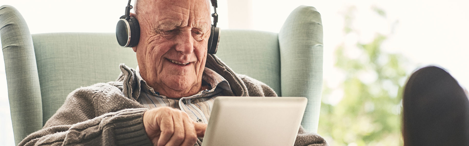 Senior man with headphones using digital tablet