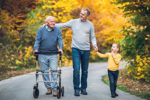 senior man walking with adult son and granddaughter outside